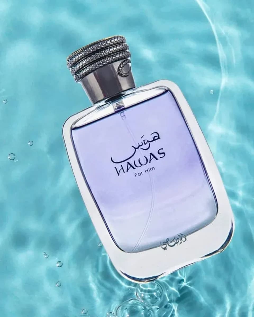 Frasco azul do Rasasi Hawas for Him 100ml com água, gotas e limão, fotografia editorial